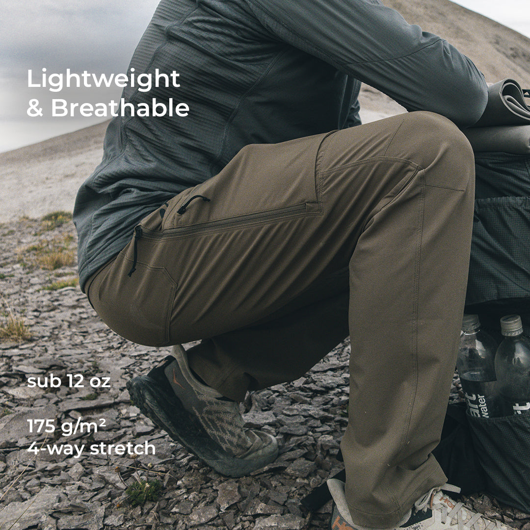 man crouching and wearing lightweight hiking pants with side zipper vents, articulated knees, and volumized pockets.