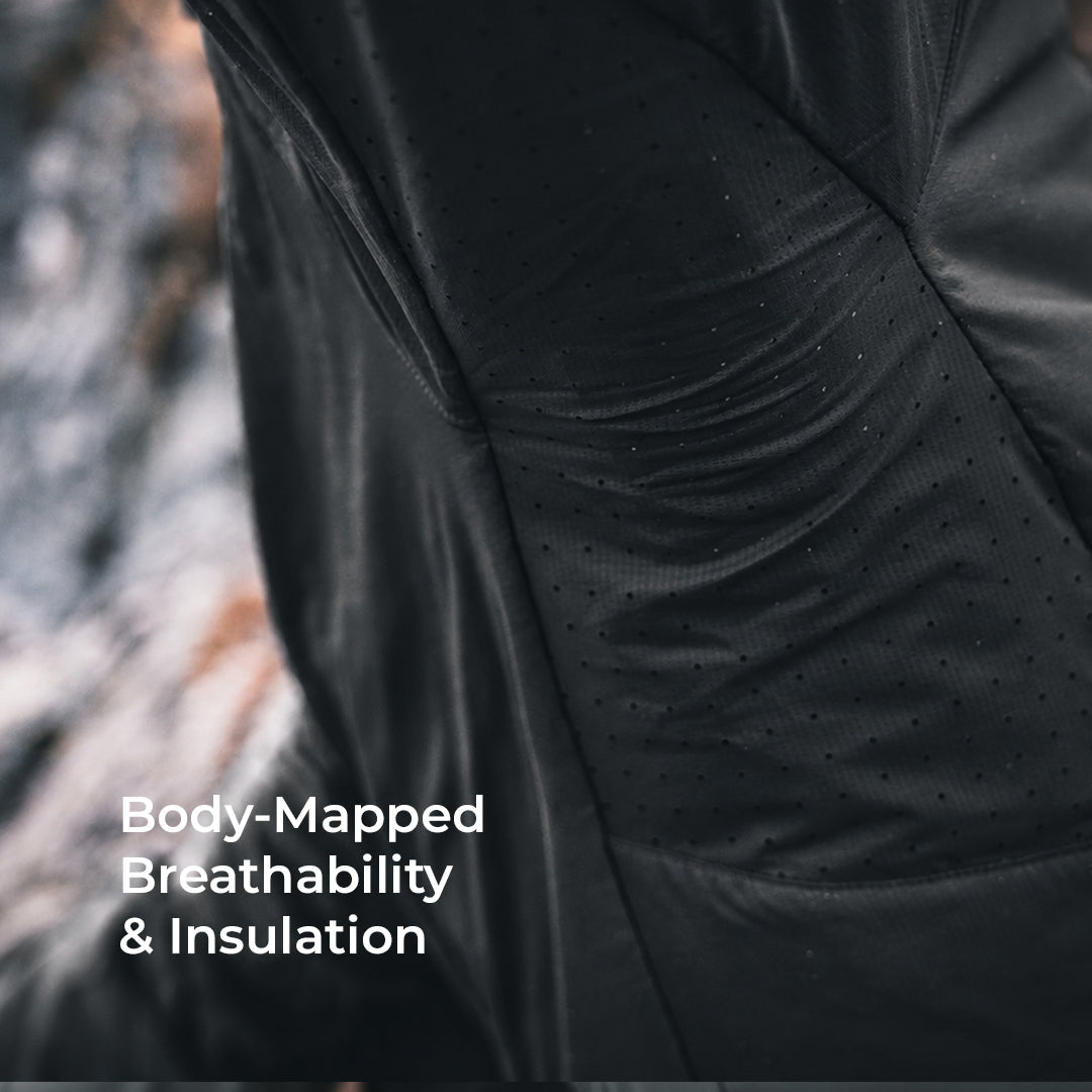 Close-up of a black insulated garment with a perforated, breathable fabric panel and white text reading 'Body-Mapped Breathability & Insulation' over a blurred outdoor background.