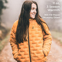 A person wearing a quilted mustard-yellow puffer jacket outdoors, with text overlay on the right reading '11 oz, 3 Season Warmth, 900 Fill Power Muscovy Down'.