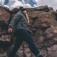 woman wearing dark gray puffy down jacket in high mountain environment.